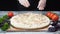 Close-up of chef`s hands in silicone gloves adding cheese to the pizza on a wooden table. Frame. Delicious pizza