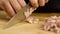 Close-up of chef slicing sausages. Stock footage. Chef cuts slices of juicy pink sausage pizza on wooden board. In