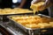 Close-up of a chef taking a melted piece of cheese from a large pan, kitchen in a hotel complex.