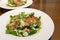 Close up of chicken Cesar salad served in a round white plate.