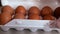 Close-up of chicken eggs are stacked in a gloved hand.