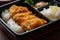 Close-up of chicken katsu bento box with rice, pickles, and miso soup