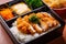 Close-up of chicken katsu bento box with rice, pickles, and miso soup