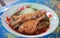 Close-up of chicken leg noodle in a soup with herbs and spices in Asian style cup.