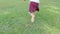 Close up of child bare feet running on the grass field in the park outdoor. Concept of Childhood happiness.