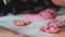 Close up of child decorating heart shaped cookies with sweet color sprinkles.