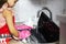 Close-up of child girl wash laptop in sink with water and detergent, wearing red apron and pink gloves.