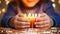 Close-up of child hands holding burning candle on christmas background