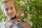 Close up of a child playing violin on green background. Portrait of girl with string and playing violin. Portrait of the little