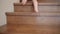 Close-up, a child`s bare feet quickly climb a wooden staircase with a wrought-iron railing