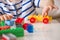 Close up of child`s hands playing with colorful plastic bricks at the table. Toddler having fun. Developing toys