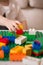 Close up of child`s hands playing with colorful plastic bricks at the table. Toddler having fun. Developing toys