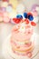 Close-up of children decorated with pink and white cake and unicorn figurine layered with lollipops for birthday on a background