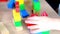 Close-up of children`s educational toys in hands of toddler, small child, a 2-year-old girl builds houses for characters from