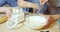 Close-up of children`s hands sifting flour into a bowl while female hands whipping cookie dough with a whisk in the kitchen.