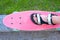 A close up of a childs leg in the sandals standing on a pink plastic skateboard, the top view. Sports lifestyle