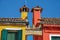 Close-up of chimneys and arch between colorful terraced houses in Burano.