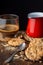 Close-up of chocolate chip cookies with red saucepan, glass cup with coffee and spoon on wooden table, black background