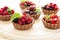Close up of chocolate tartlets with chocolate cream, fresh strawberries, raspberries, blueberries, red currants and cherries