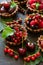 Close up of chocolate tartlets with chocolate cream, fresh strawberries, raspberries, blueberries, red currants and cherries