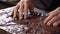 A close-up of a chocolatier\'s hand gently spreading Couverture Chocolate onto a marble slab