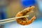 Close up chopsticks keep on the fried shrimp with blurred background.