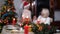 Close-up of Christmas candle burning on decorated table with blurred boy putting on New Year hat and woman showing