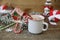 Close-up christmas composition with gingerbread house, mug of cocoa, caramel canes gingerbread house and decorations on wooden