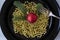 close up of christmas decorations, gold beads, fir tree branches and red christmas ball in black plate like italian