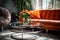 Close up of chrome coffee table near beige sofa and orange chair against window. Mid-century home interior design of living room