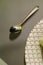 Close up of a chrome spoon with a silver plate on one side on a transparent glass table