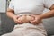 Close up of chubby woman holding her belly fat on the sofa. Diet lifestyle to reduce belly and shape up healthy, abdominal muscle