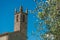 Close-up of church and bell tower with trees around in the hamlet of Monteriggioni.