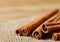 Close up cinnamon sticks and coffee on hessian canvas with wooden background