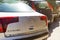 Close-up of the Citroen logo and tail lights on the rear hood of a silver car parked on a city street on a sunny day