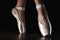 Close-up classic ballerina`s legs in pointes on the black floor