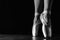 Close-up classic ballerina`s legs in pointes on the black floor