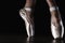 Close-up classic ballerina`s legs in pointes on the black floor