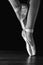 Close-up classic ballerina`s legs in pointes on the black floor