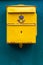 Close up of a classic yellow public postal mail box with a mail symbo.