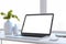 Close up of clean designer office desktop with white mock up computer screen, decorative vase with plant, other objects and window