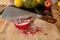 Close-up of a cleaver stuck in a pomegranate on a wooden cutting board