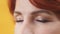 Close up of closed eyes with purple and gold eyeshadow of mature red hair woman