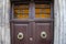 Close up of closed wood door with door knobs, handles and cast iron latice work