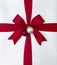 Close-up closeup of Christmas gift present with bright red satin ribbon bow and silver white wrapping paper. Simple, graphic,