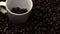 Close up of coffee bean falling in to coffee cup surrounded by bean. Comestible.