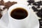 Close-up of coffee cup in front of different coffee beans