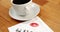 Close-up of coffee cup with lipstick mark and message written on tissue