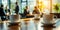 Close-up of coffee cups on a conference room table with blurred business professionals engaging in discussions in a bright