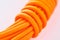 Close-up on a coil of orange paracord on white background